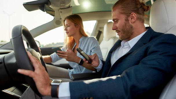 Young caucasian couple holding smartphones inside car - Photo, Image