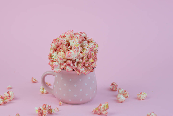 Een close-up shot van een cupof popcorn geïsoleerd op een roze achtergrond - Foto, afbeelding