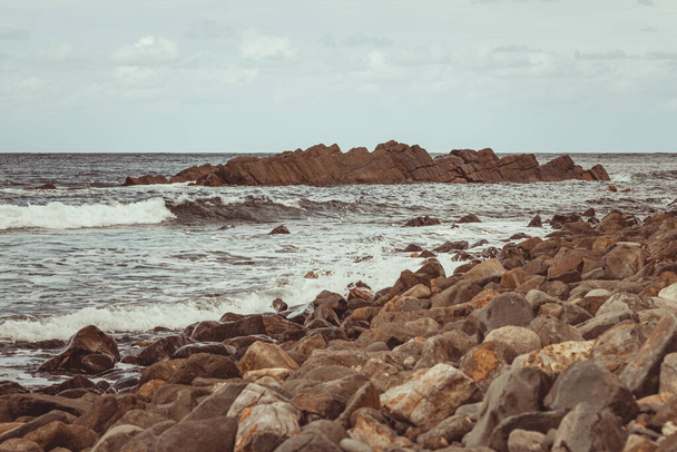 Скелястий пляж біля спокійного моря, захопленого вдень
 - Фото, зображення
