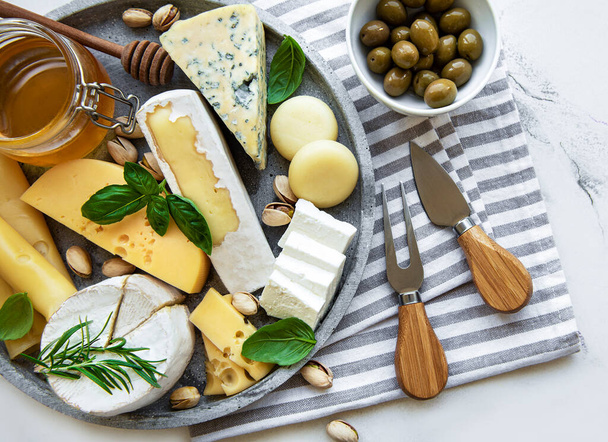 Différents types de fromages, raisins, miel et collations sur fond de marbre - Photo, image