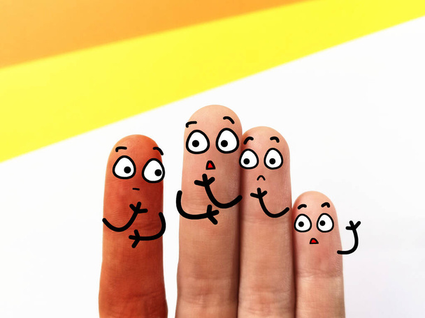 Cuatro dedos están decorados como cuatro personas. Tres de ellos discriminan a un amigo que tiene diferente color de piel. - Foto, imagen