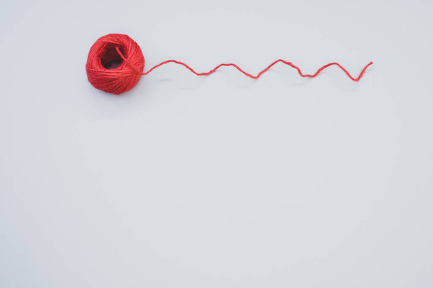 Un primer plano de hilo de lana rojo brillante sobre un fondo gris - Foto, Imagen
