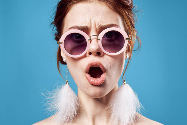 kobieta nosi okulary przeciwsłoneczne kolczyki luksusowe emocje zbliżenie niebieski tło - Zdjęcie, obraz