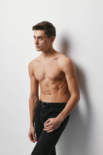 Sporty man with a naked torso on a light background and dark trousers model - Fotografie, Obrázek
