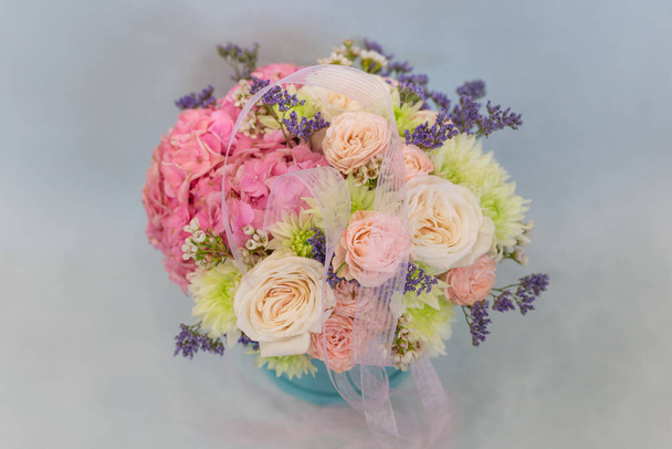 Flower arrangement in a hat box. On a light background. Bouquet of light, delicate flowers. - Фото, зображення