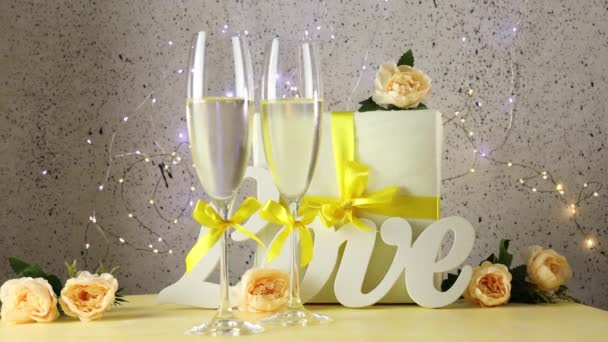 Tafel met liefdesbrieven, cadeau en rozen, bokeh lichten, Sint Valentijnsdag of bruiloft wenskaart gerold van cirkels achter twee champagne glazen met gele bogen tafel met liefdesbrieven, cadeau en rozen, bokeh lichten, - Video