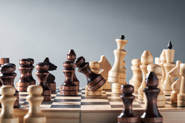 Wooden chess pieces on a chessboard, white queen defeats black pawn, the concept of strategy, planning and decision making. The concept of leadership and teamwork to achieve success. - Фото, изображение