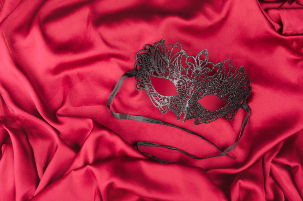 Benátská maska s černým peřím na červené látce - Fotografie, Obrázek
