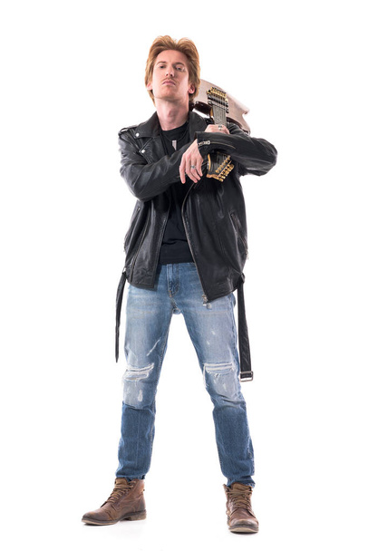 Cocky στάση macho rocker σε δερμάτινο μπουφάν μεταφέρουν ηλεκτρική κιθάρα κοιτάζοντας κάμερα με το κεφάλι πίσω. Πλήρες σώμα απομονωμένο σε λευκό φόντο.  - Φωτογραφία, εικόνα