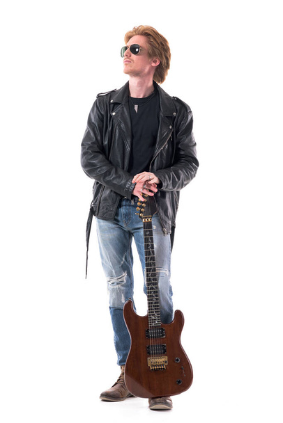guitariste de musique macho rock réfléchi dans une veste en cuir tenant la guitare levant les yeux. Corps entier isolé sur fond blanc.  - Photo, image