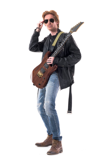 Модний рудий красивий рок-гітарист позує тримаючи сонцезахисні окуляри. Повне тіло ізольоване на білому тлі
.  - Фото, зображення