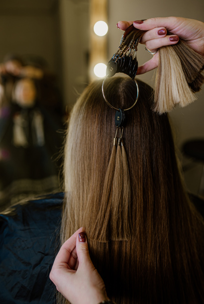 Στο κομμωτήριο, η κομμώτρια επιλέγει δείγμα μαλλιών για την περούκα. Κλείσιμο - Φωτογραφία, εικόνα