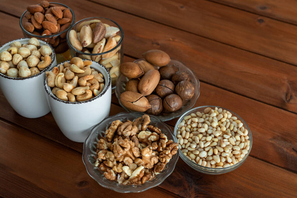 Mixed nuts in bowl on wooden table - Photo, Image