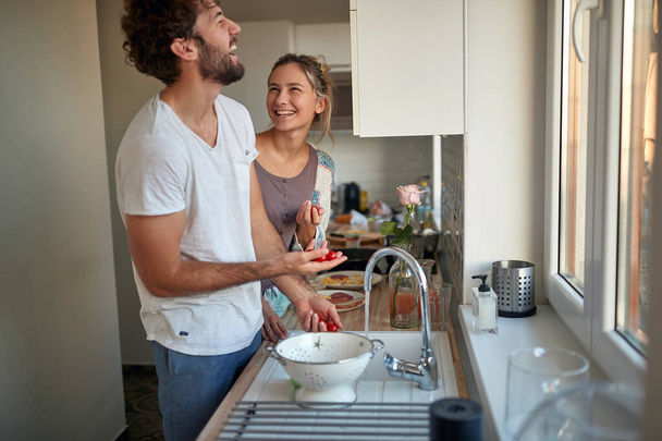 Una joven pareja enamorada bromeando mientras preparan un desayuno juntos en una hermosa mañana. Relación, juntos, cocina, amor - Foto, Imagen