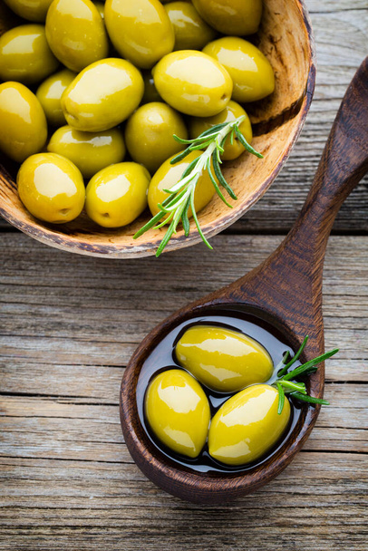 Fresh olives and gray background. Olives in bowl and spoon. - Foto, afbeelding