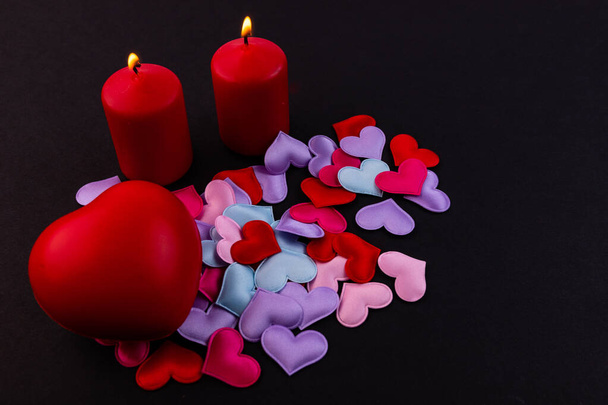 A lot of little hearts and two candles on a black background - Φωτογραφία, εικόνα