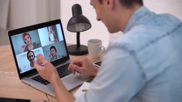 technologia, zdalna praca i koncepcja stylu życia - szczęśliwy człowiek z laptopem mającym czat wideo i machającą ręką w biurze - Materiał filmowy, wideo