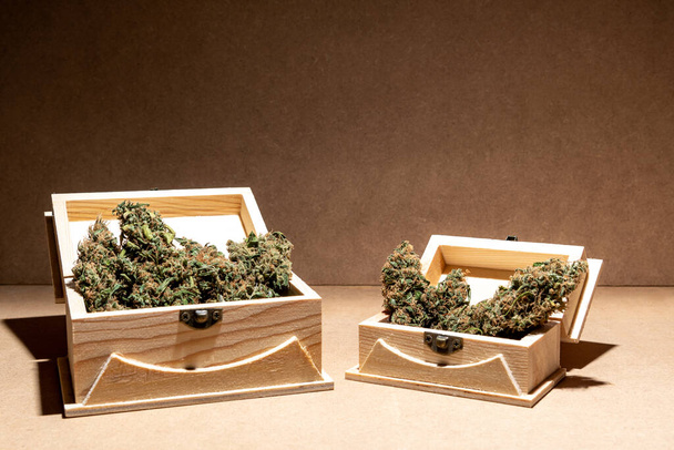 Готовые к использованию медицинские бутоны марихуаны внутри двух деревянных коробок. Селективный фокус. - Фото, изображение