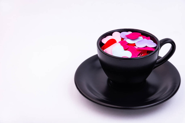 Black cup and saucer and small hearts inside on a white background - Fotoğraf, Görsel