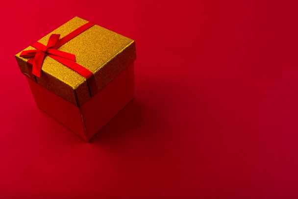 Small gift with red bow on red background. Free space for your text. - Foto, Bild