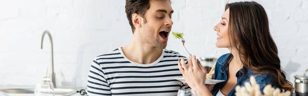 happy woman holding plate and feeding boyfriend with lettuce, banner - Foto, Imagem