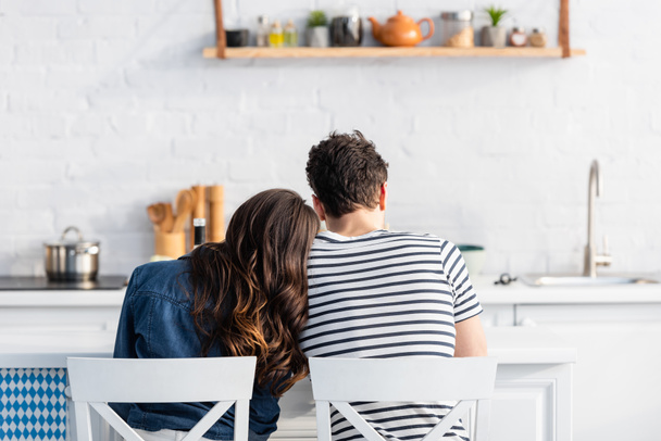 back view of woman and man sitting on chairs in kitchen  - Foto, imagen