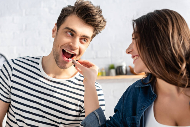 happy woman feeding man with cherry tomato - Photo, Image