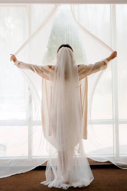 girl the bride happily opens the curtains of a large window - Fotoğraf, Görsel