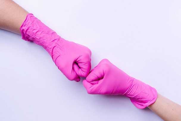 Fists on a white background. Pink latex gloves and a new welcome concept with side space. - Photo, Image