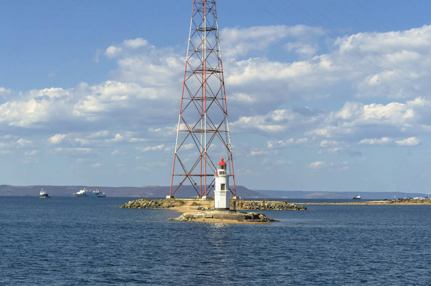 Lighthouse Tokarevskaya cat with power line view and sailing ships on sunny day - Fotó, kép