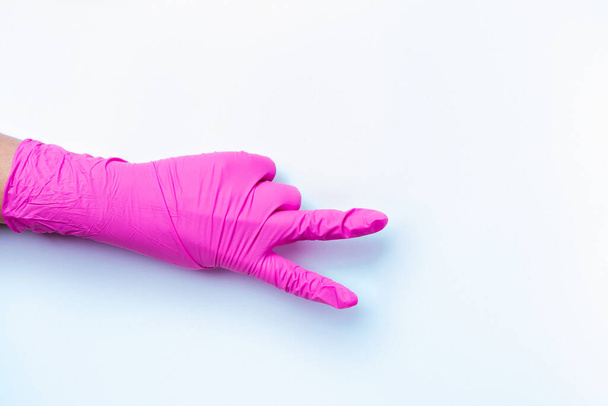 A paramedic hand in a pink latex glove shows the victory sign on a white background with blank space. - Photo, image