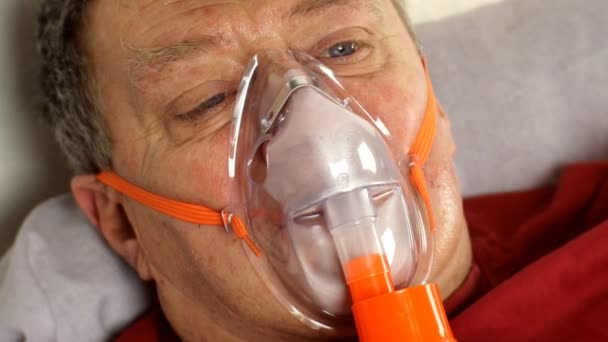 Hombre de mediana edad enfermo está respirando a través de la máscara de oxígeno mientras está acostado en la cama. Tratamiento del asma, alergias, bronquitis, neumonía en Covid-19 y enfermedades respiratorias. Primer plano. - Metraje, vídeo