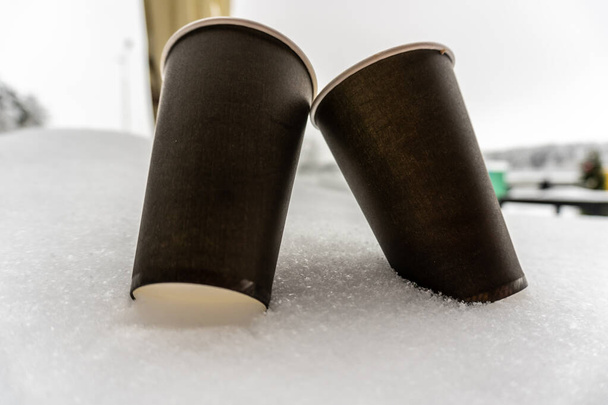 Δύο χάρτινα φλιτζάνια με καφέ ζεσταίνονται σε ένα μαντήλι στο χιόνι, χειμωνιάτικη ιστορία αγάπης - Φωτογραφία, εικόνα