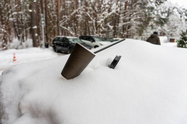 Bir kahve fincanı, bir sokak kafesinin yanındaki karda pipetle duruyor. - Fotoğraf, Görsel