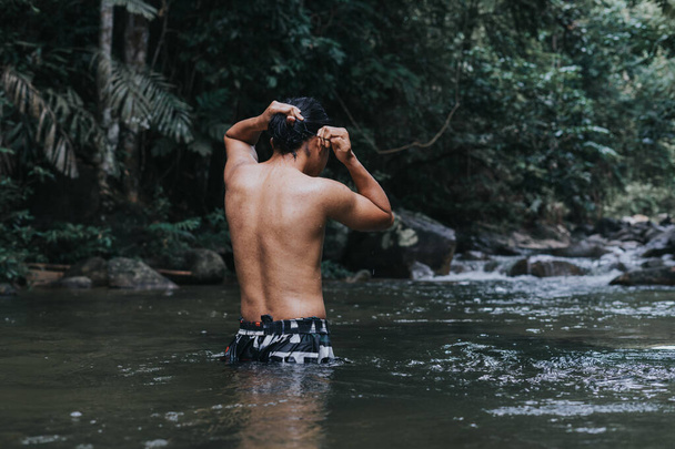 A male traveler in the rain forest pool stream or waterfall.View from behind.Healthy and active lifestyle.Camping and hiking. - Foto, afbeelding
