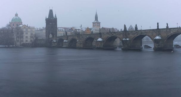 Most Karola na Wełtawie i posągi na moście i światło od świateł ulicznych i upadły sen zimą wczesnym wieczorem w centrum Pragi - Zdjęcie, obraz