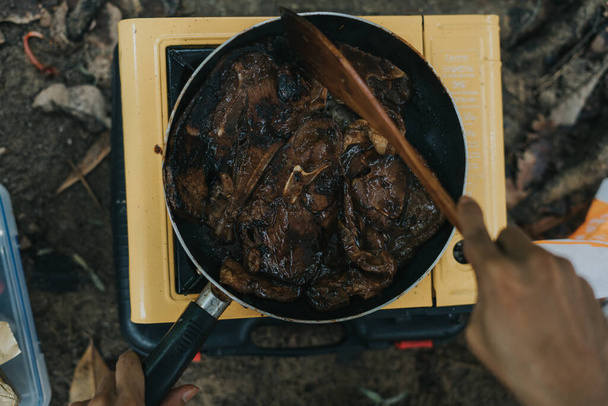 Dopełnij widok z bliska na rękę człowieka podczas grillowania jagnięciny na kuchence kempingowej. - Zdjęcie, obraz