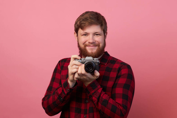 Hand of young hispanic man holding vintage camera over isolated pink background. - Фото, изображение