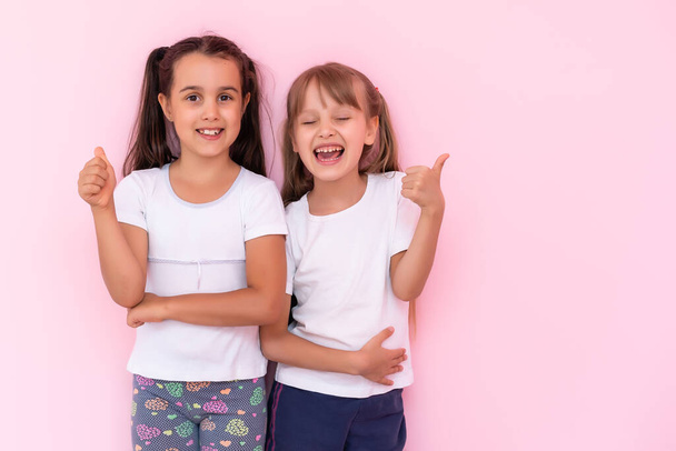 Two little girls - best friends, isolated over on a pink background - Foto, imagen