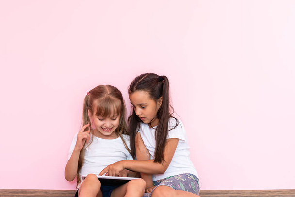 Kleine meisjes spelen op een tablet computer apparaat op de vloer - Foto, afbeelding