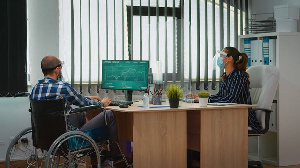 Gerente viene con silla de ruedas en el lugar de trabajo con máscara - Foto, Imagen