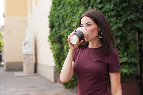 beautiful brunette drinking coffee on the street in the summer - Фото, изображение