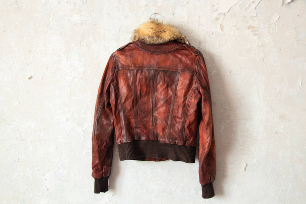 red fur leather winter women jacket hanging on a hanger on a white wall indoors - Foto, Bild