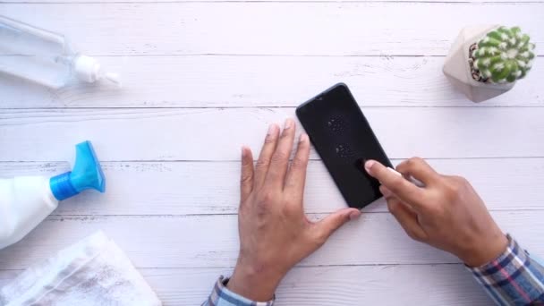 άνθρωπος σκουπίστε επιφάνεια smart phone με αντιβακτηριακό υγρό για την πρόληψη του ιού  - Πλάνα, βίντεο