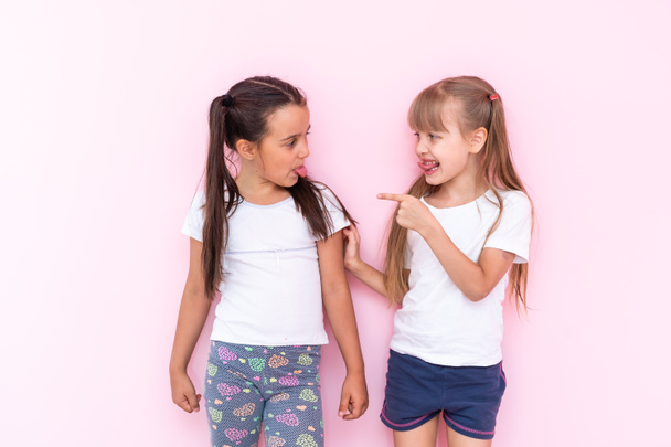 Twee meisjes vechten om een roze achtergrond - Foto, afbeelding