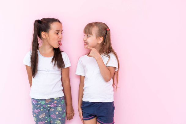 Dos chicas peleando por un fondo rosa - Foto, imagen