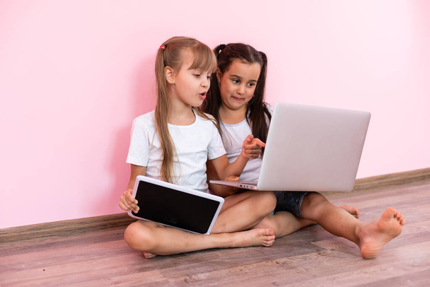 Дві дівчинки сидять перед ноутбуком і сміються, зблизька, позитивні емоції, розваги в Інтернеті для дітей. - Фото, зображення