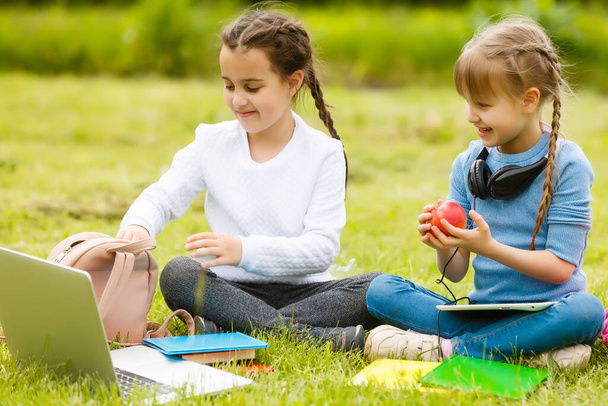 Kinder auf dem Picknick auf dem Schulhof kommen und essen Mittagessen in Schachteln. Eltern kümmern sich um Kinderbetreuung. - Foto, Bild