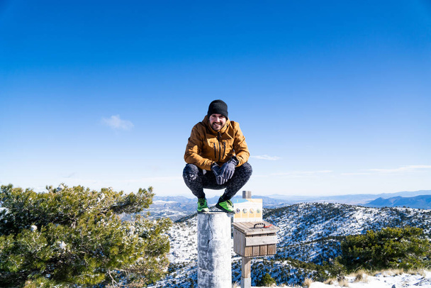 Image of a man enjoying the views on the snowy top of a mountain - Фото, изображение