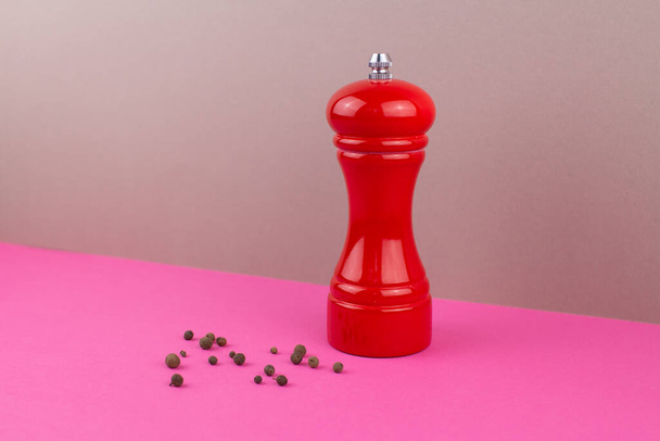 a red kitchen pepper shaker for ground pepper on the table - Foto, Imagen